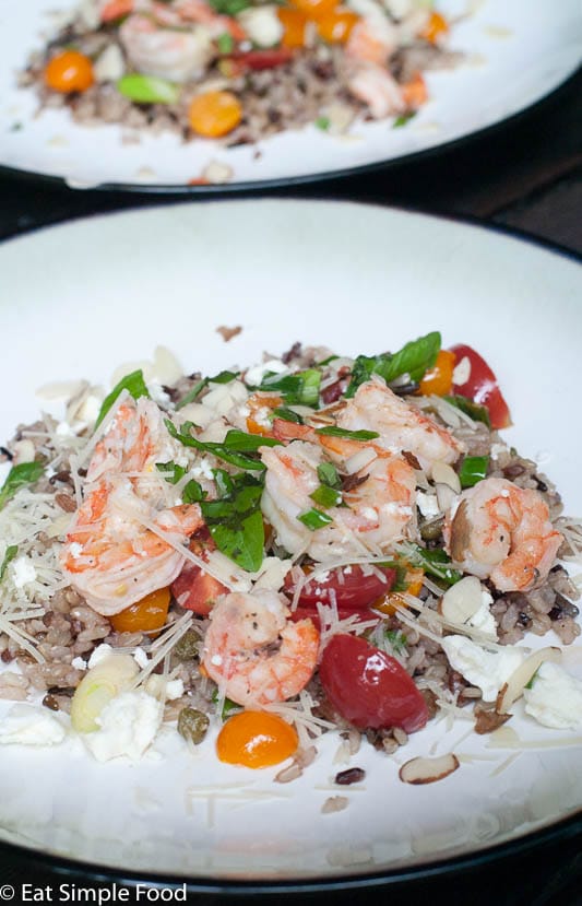 Lemon Shrimp, Capers, halved cherry tomatoes with sliced green onions over wild rice. Almond and Parmesan cheese garnish.