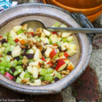 Apple, Celery, Raisin & Walnut Salad In A Brown Dish With a Spoon