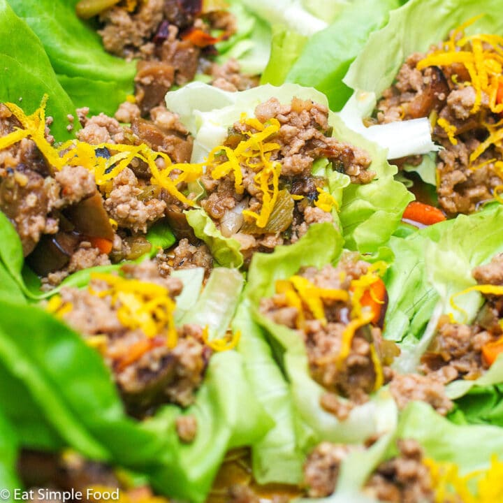 Close Up of Sauteed ground pork and veggies stuffed in a lettuce wrap and topped with orange zest.