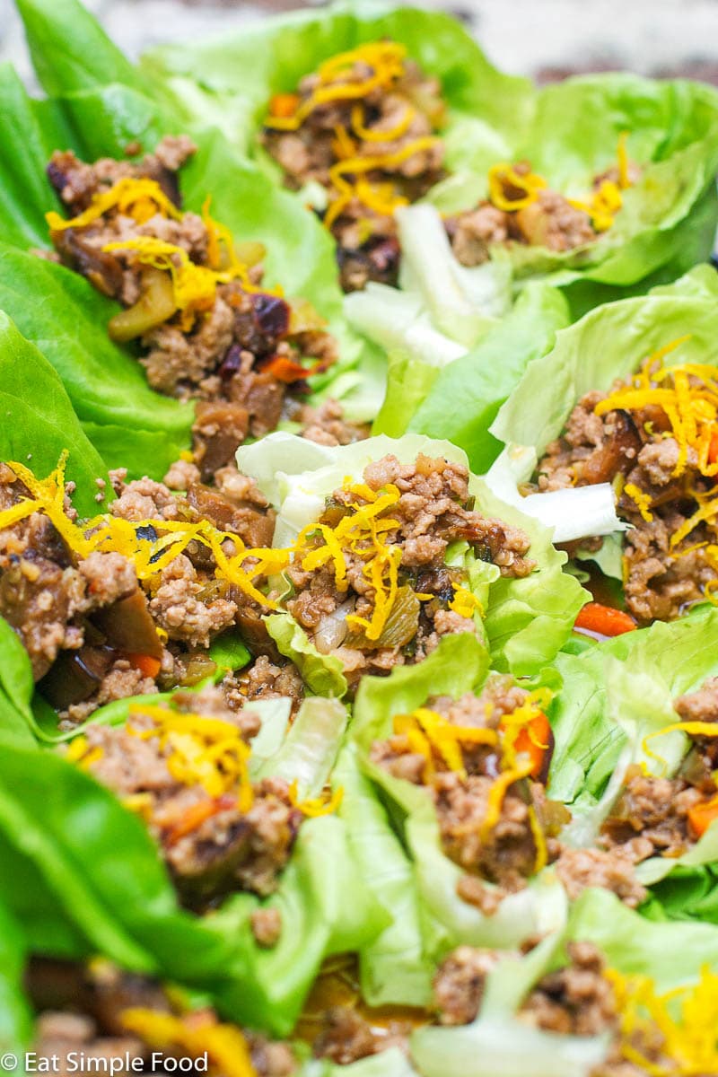 Close Up of Sauteed ground pork and veggies stuffed in a lettuce wrap and topped with orange zest.