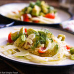 2 white plates with thin sliced fennel, chunks of avocado and quartered cherry tomato salad