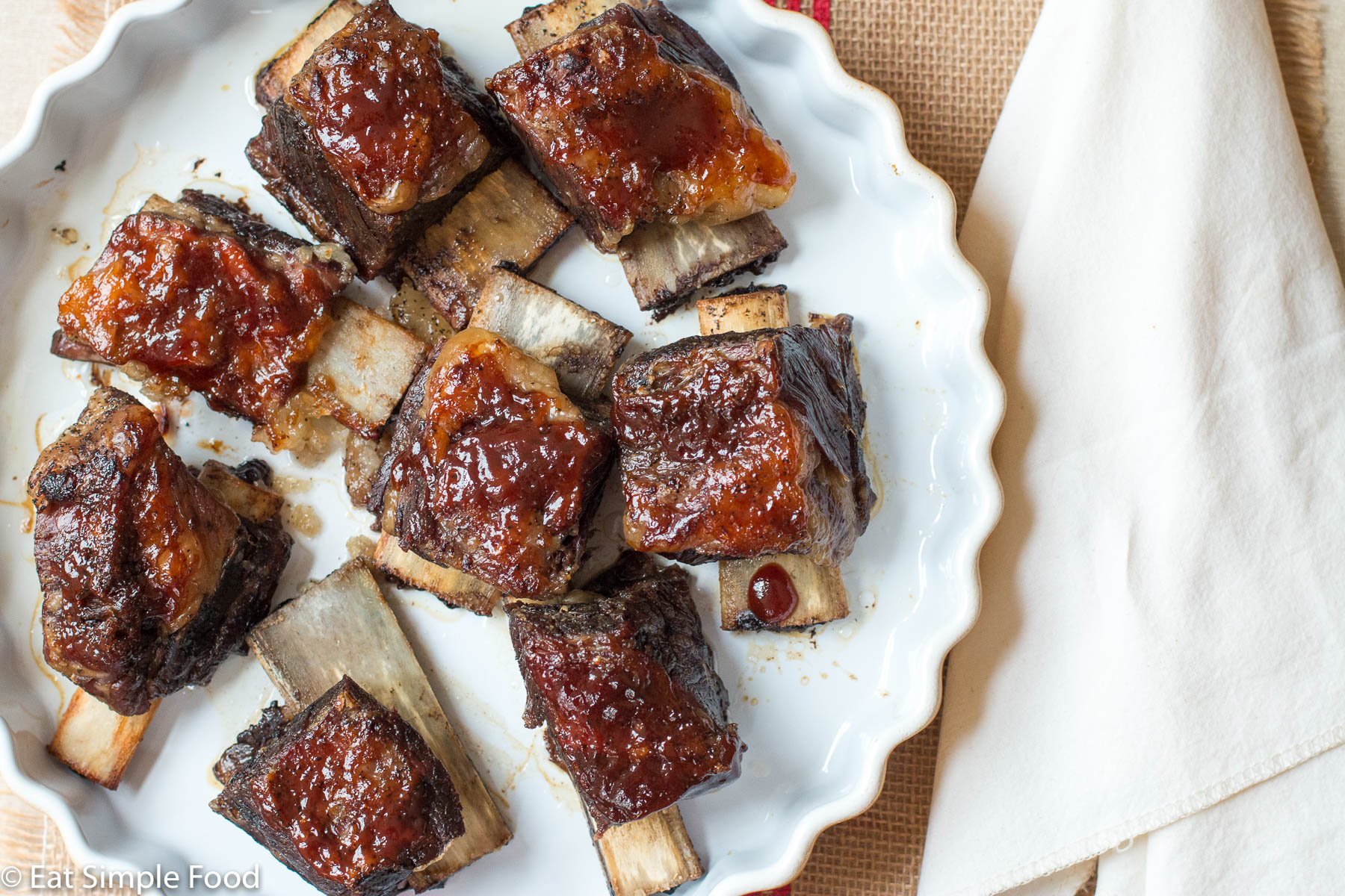 Braised & Seared Beef Bone In Short Ribs with BBQ Sauce In A Yellow Shallow Round Baking Dish