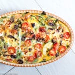Baked Mediterranean Frittata in Oval Baking Pan with cherry tomatoes, spinach, eggs, feta, capers, and olives