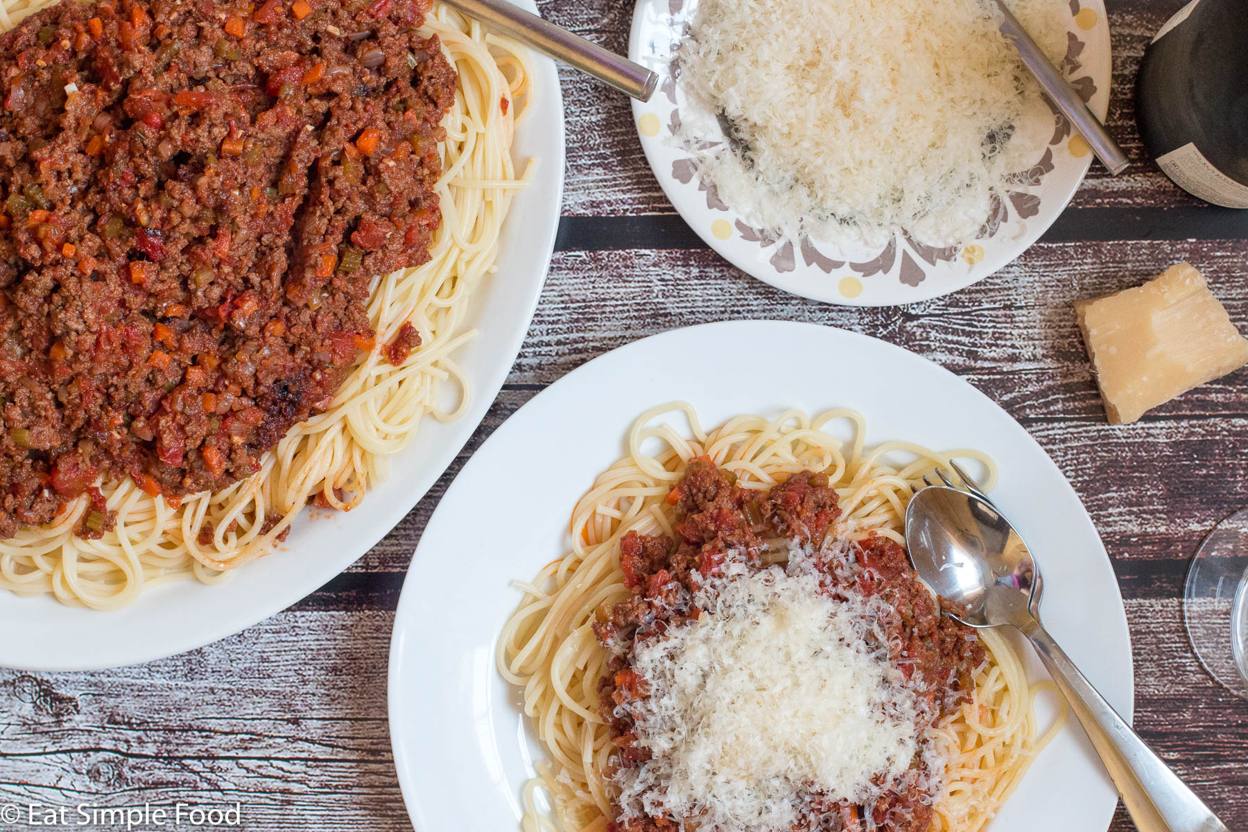 Beef Bolognese on a white plate with a plate and garnish of Parmesan Cheese | EatSimpleFood.com