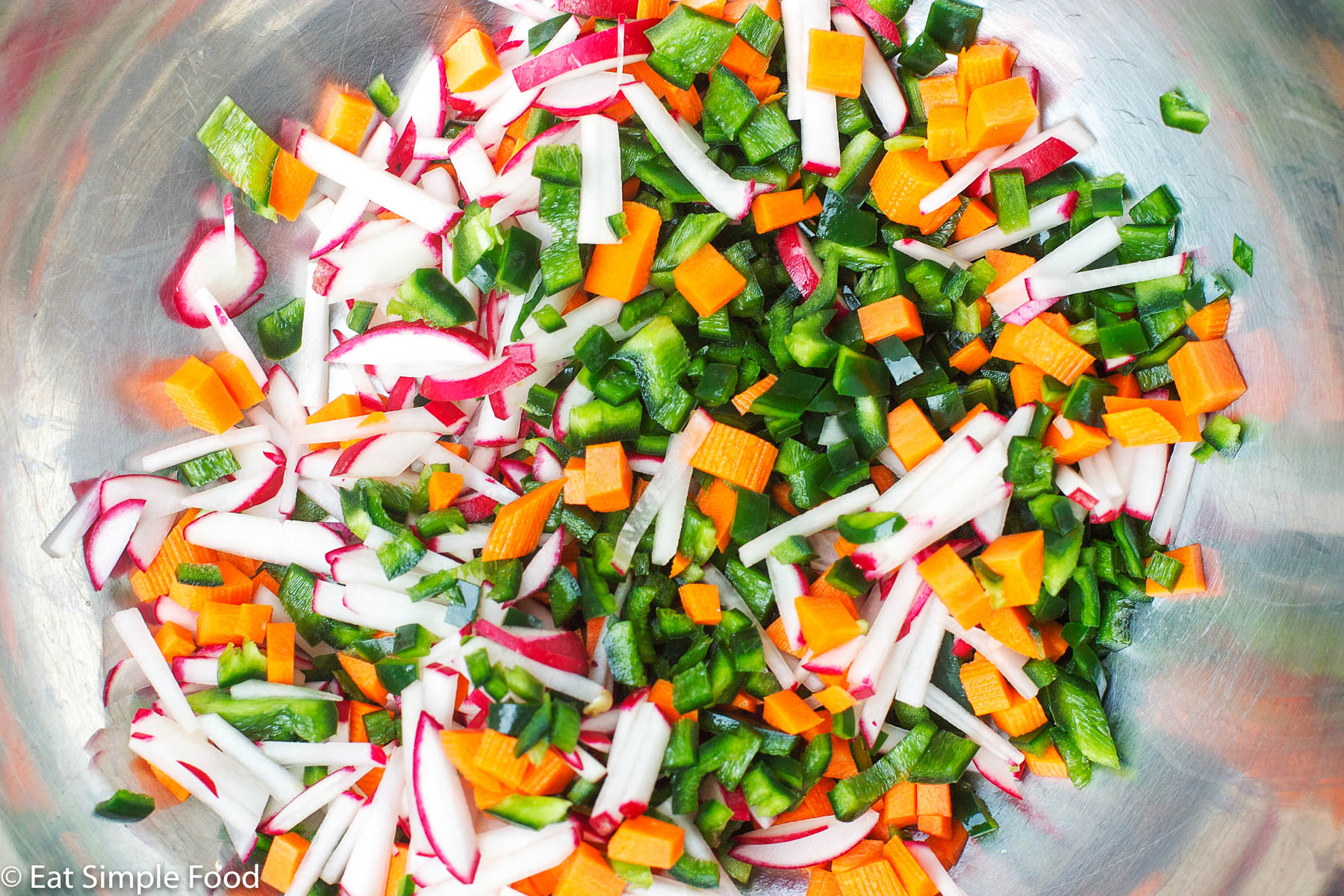 Bowl of chopped vegetables (carrots, radishes, peppers. Top view close up.