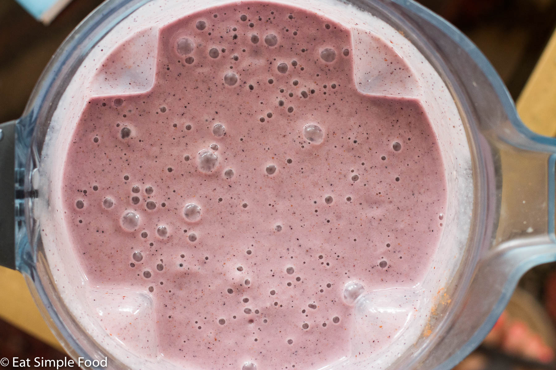 Top down view close up of a blender with purple blended up ingredients.