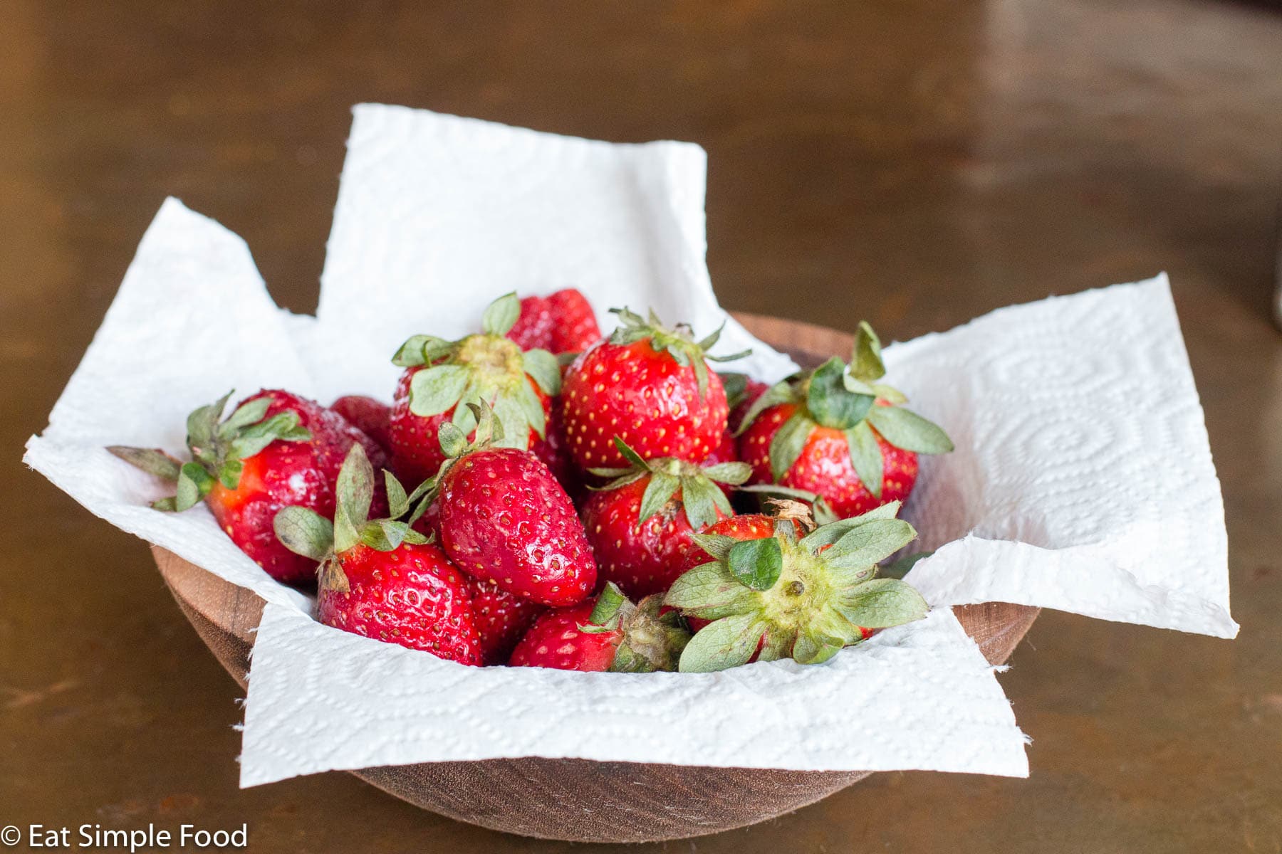 Fresh strawberries in a paper towel lined bowl.