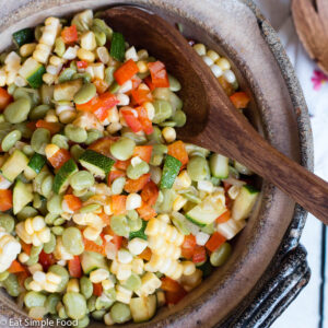 Top View Corn & Lima Bean Succotash with diced Zucchini In A brown Bowl with a Wood Spoon