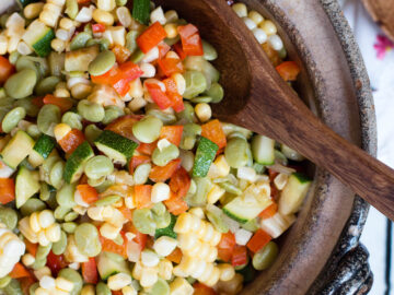 Top View Corn & Lima Bean Succotash with diced Zucchini In A brown Bowl with a Wood Spoon