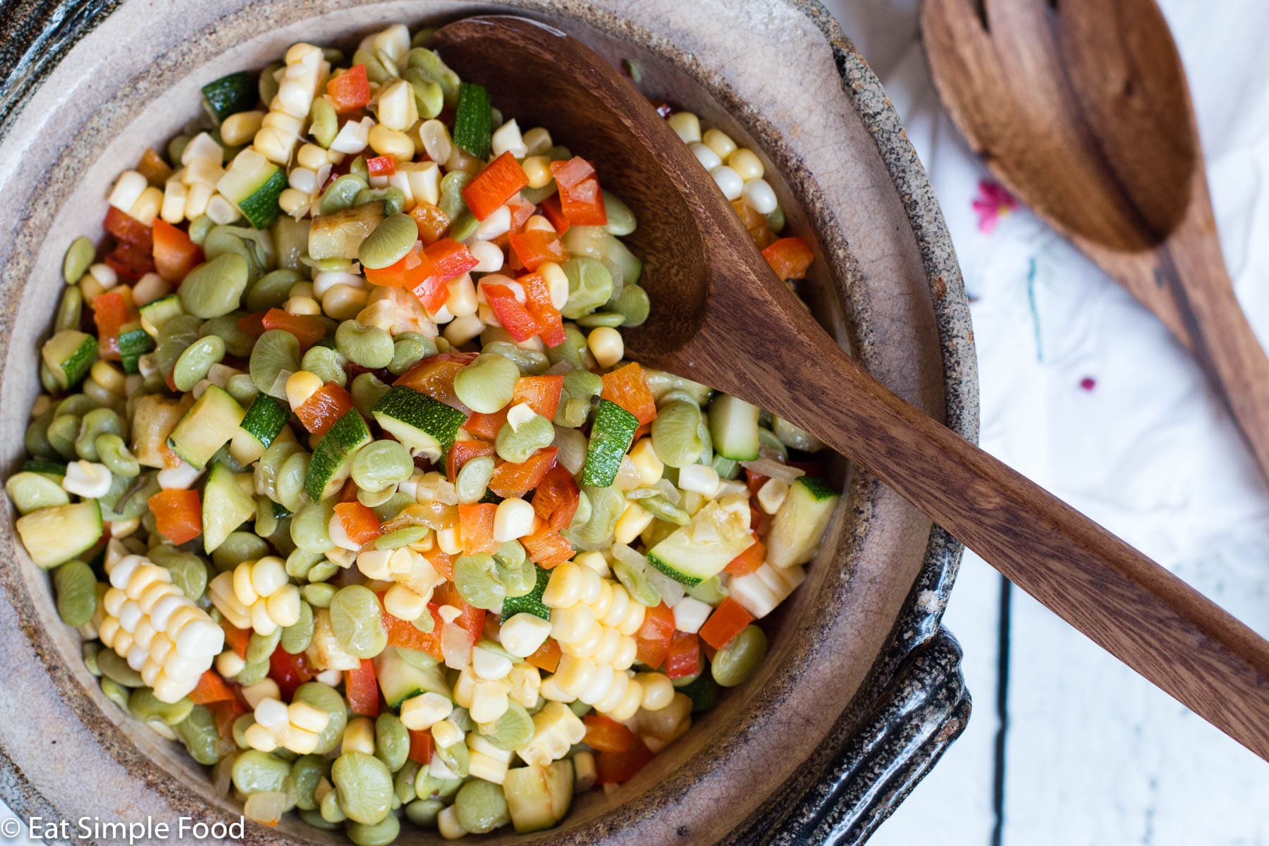 Top View Corn & Lima Bean Succotash with diced Zucchini In A brown Bowl with a Wood Spoon