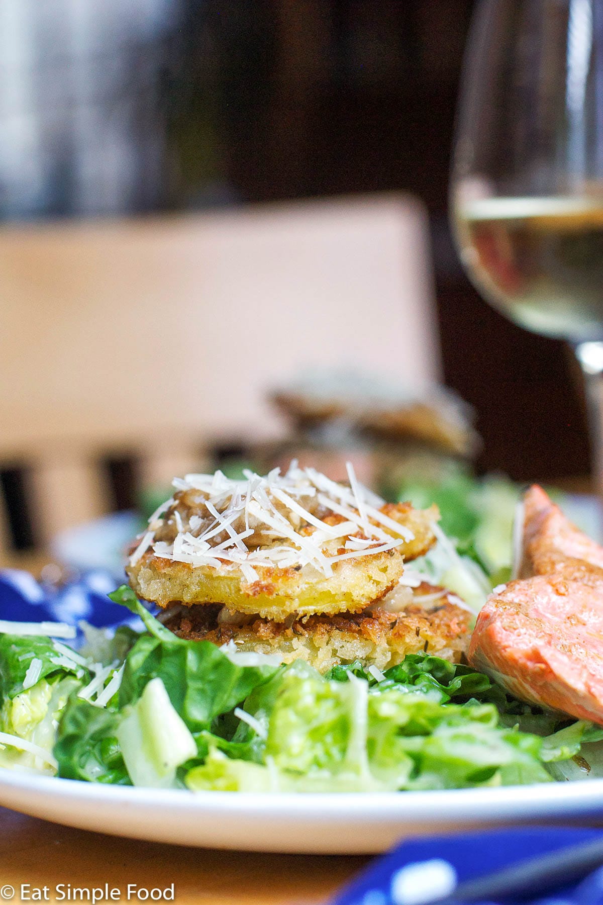 2 layered Fried Green Tomatoes Over a bed of Caesar Salad w/ a small piece of cooked salmon.