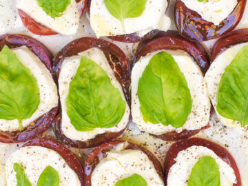 Close up of Red Purple Tomato slices, Mozzarella cheese slices, and basil leaf.