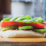 Sliced Tomato, Sliced Cucumber, Creamy Goat Cheese and Basil leaves on an open faced ciabatta bread slice
