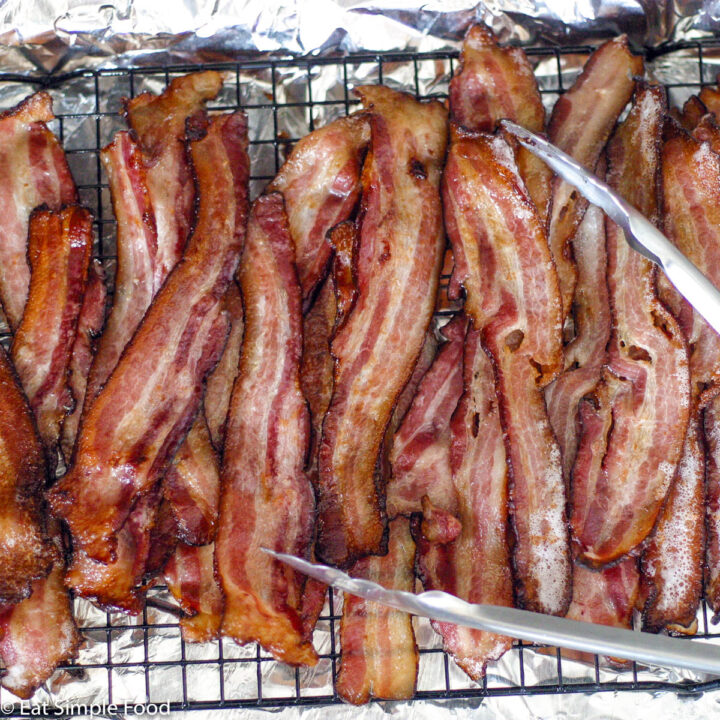 Brown Roasted Crispy bacon on an elevated wire rack over an aluminum lined sheet pan.