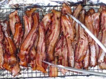 Brown Roasted Crispy bacon on an elevated wire rack over an aluminum lined sheet pan.