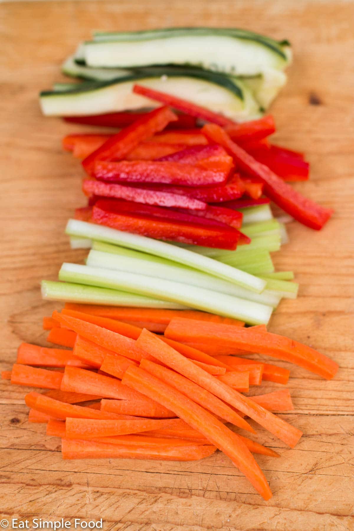 Wood Cutting board with sliced carrots, celery, red peppers, and cucumbers