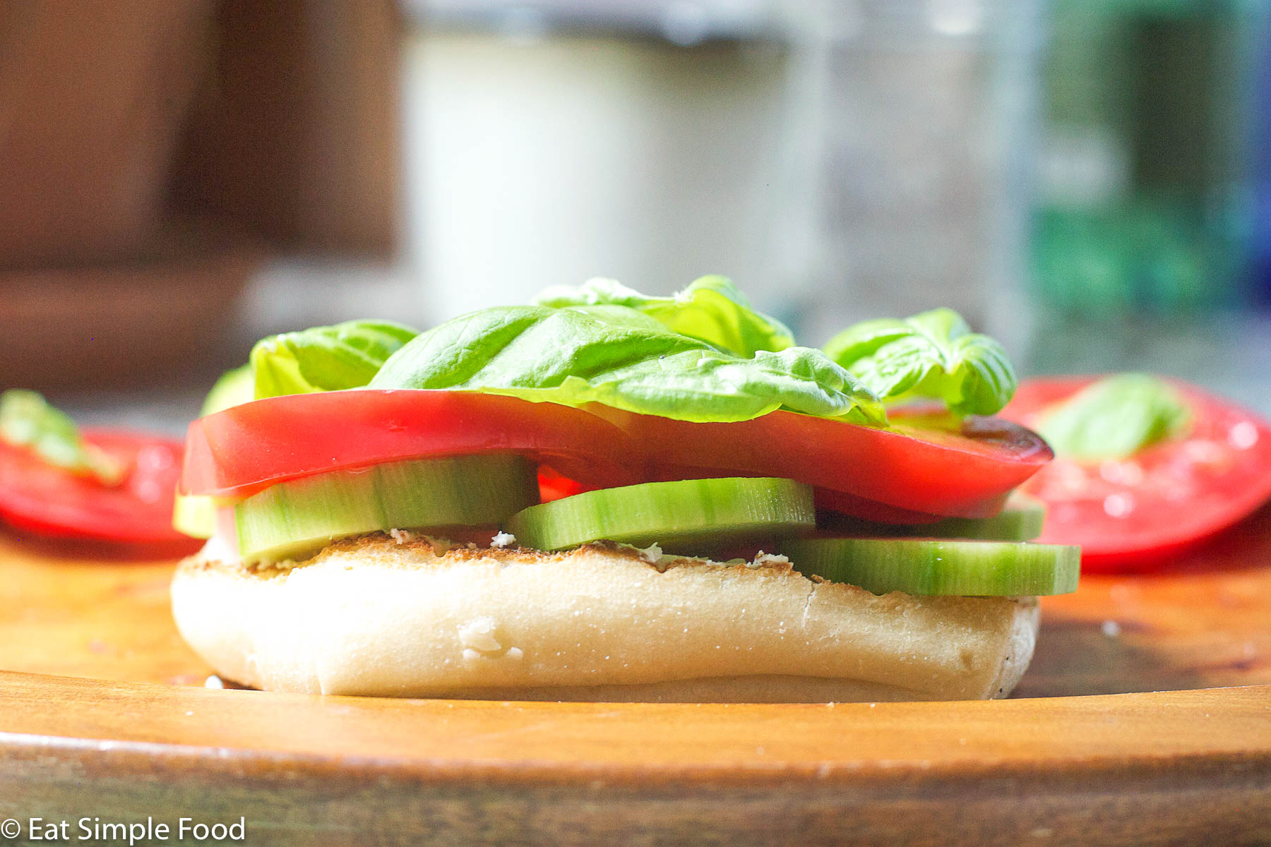 Sliced Tomato, Sliced Cucumber, Creamy Goat Cheese and Basil leaves on an open faced ciabatta bread slice