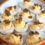 Close up of Deviled Eggs Topped with Chow Chow (Pickled Tomatoes) on a white plate
