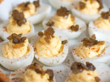 Close up of Deviled Eggs Topped with Chow Chow (Pickled Tomatoes) on a white plate