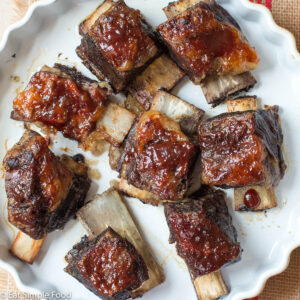 Braised & Seared Beef Bone In Short Ribs with BBQ Sauce In A Yellow Shallow Round Baking Dish