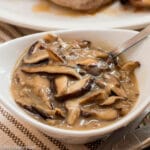 Chunky sliced Mushroom Gravy Recipe in White Bowl with a spoon sticking out.