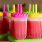 Pink Watermelon Popsicles in plastic molds with coloful tops. Around 14 popsicles.