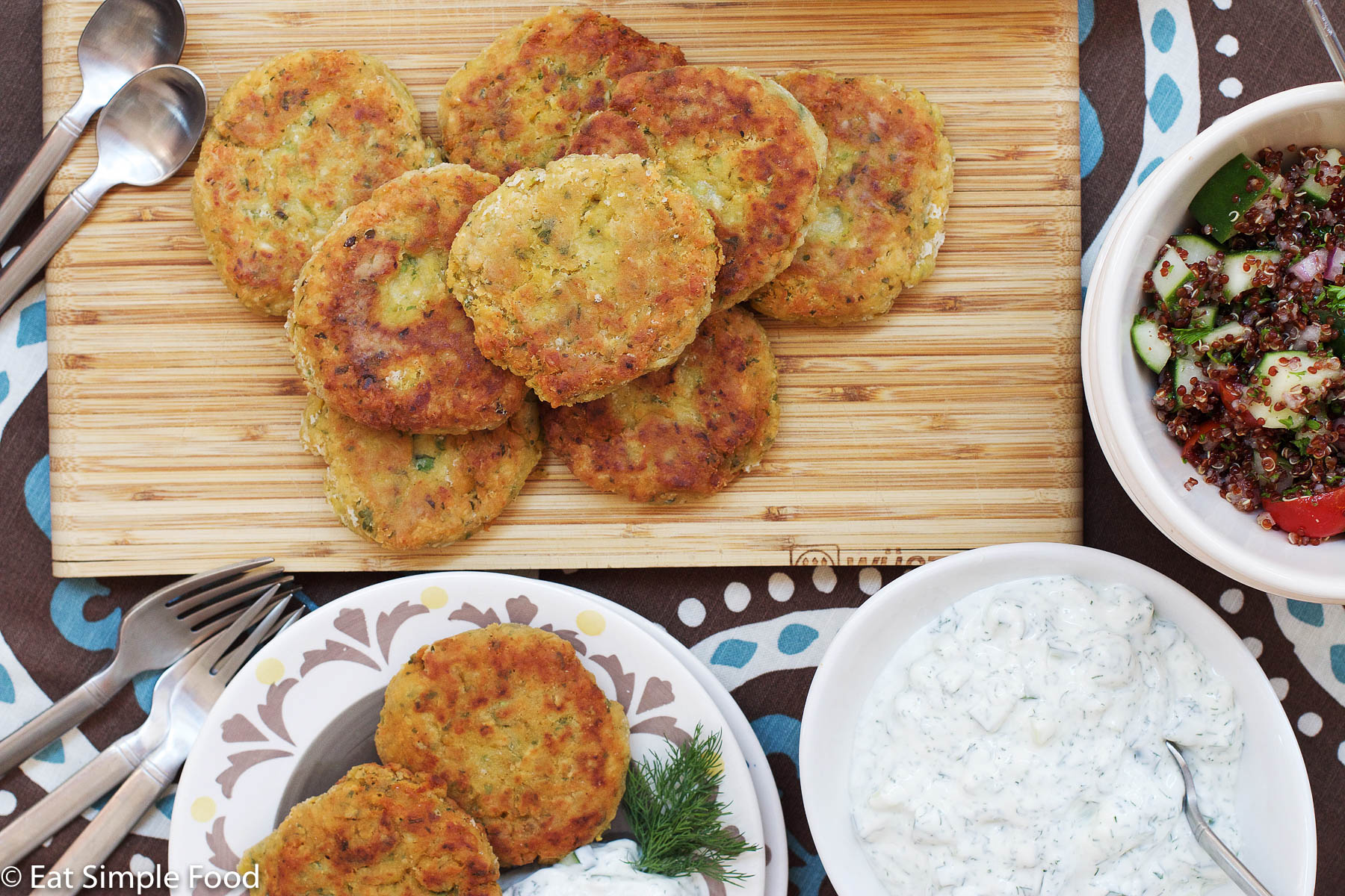 Top View of Falafels on a wood cutting board with a side plate of 2 falafels and a bowl of white cucumber tzatziki