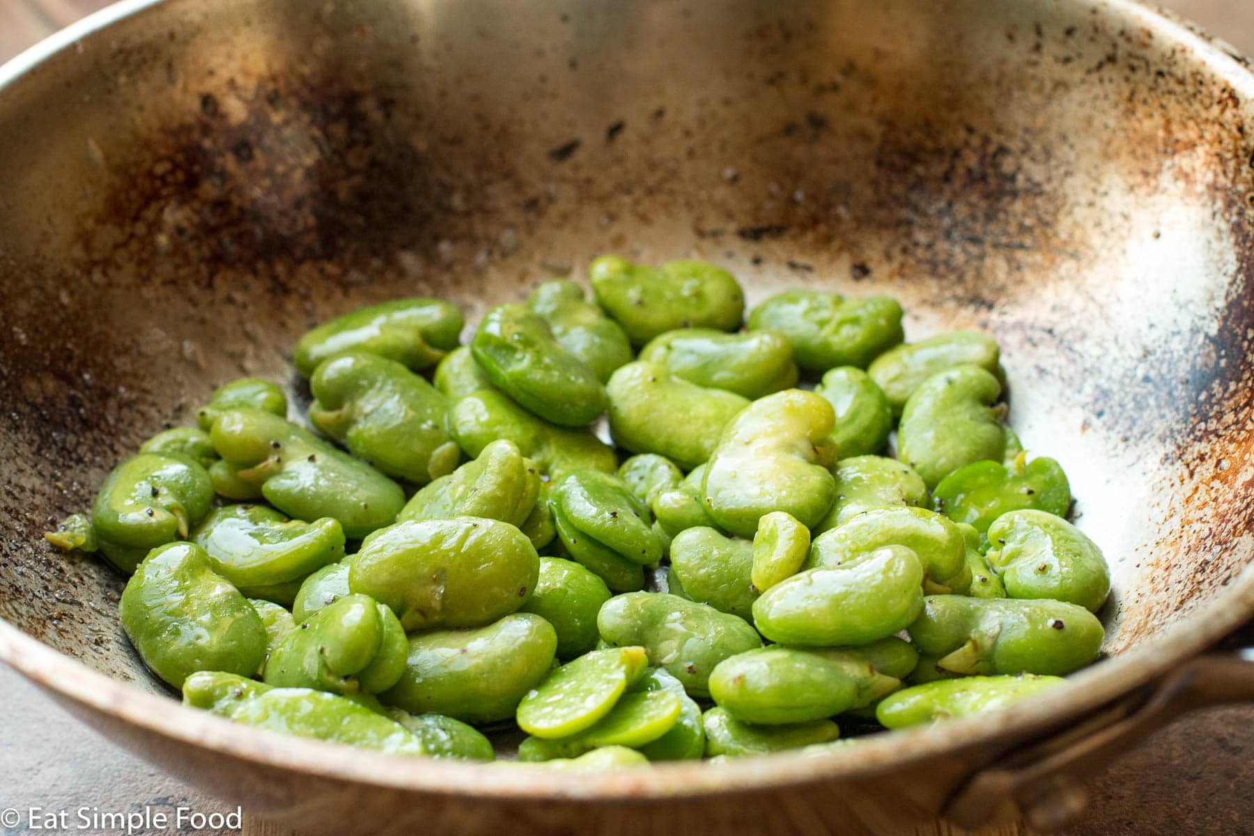 Bright green Fava (AKA Lima) Beans cooked in a stainless steel pan. Close up