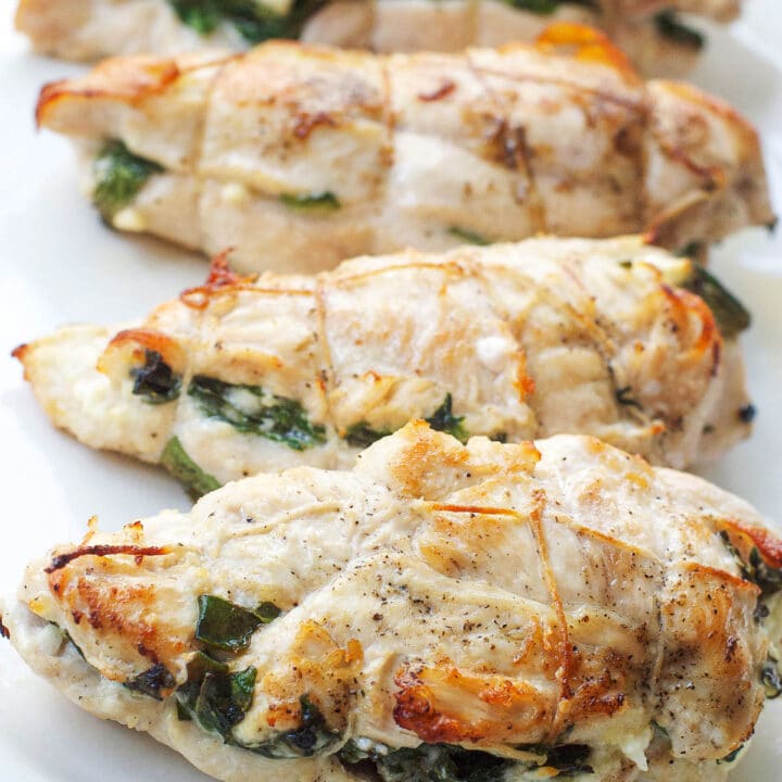 4 Chicken Breasts Stuffed With Feta and Spinach On A White Plate. Vertical view.