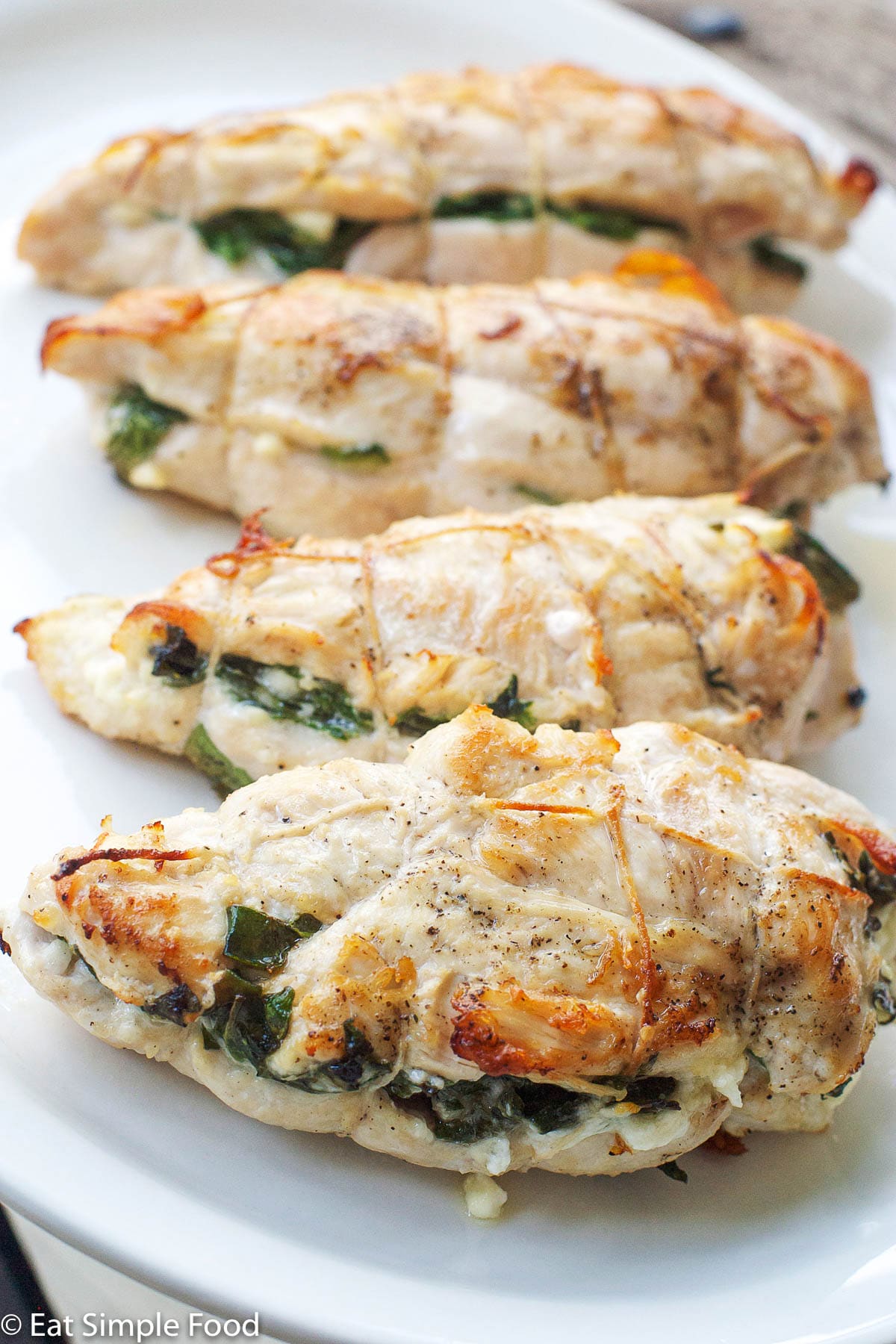 4 Chicken Breasts Stuffed With Feta and Spinach On A White Plate. Vertical view.