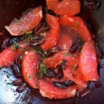 PInk grapefruit segments with black kalamata olives and fresh chopped rosemary in a wood bowl. close up. top view.