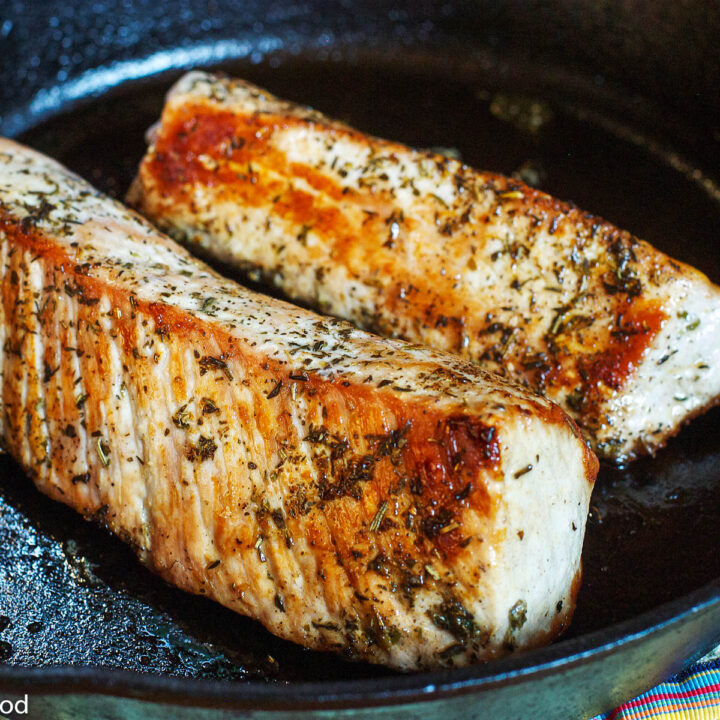 2 Pieces of Herbed Pork Tenderloin seared In A Cast Iron Skillet