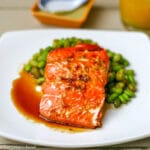 Salmon on square plate with ginger & soy sauce over a bed of shelled edamame - Eat Simple Food