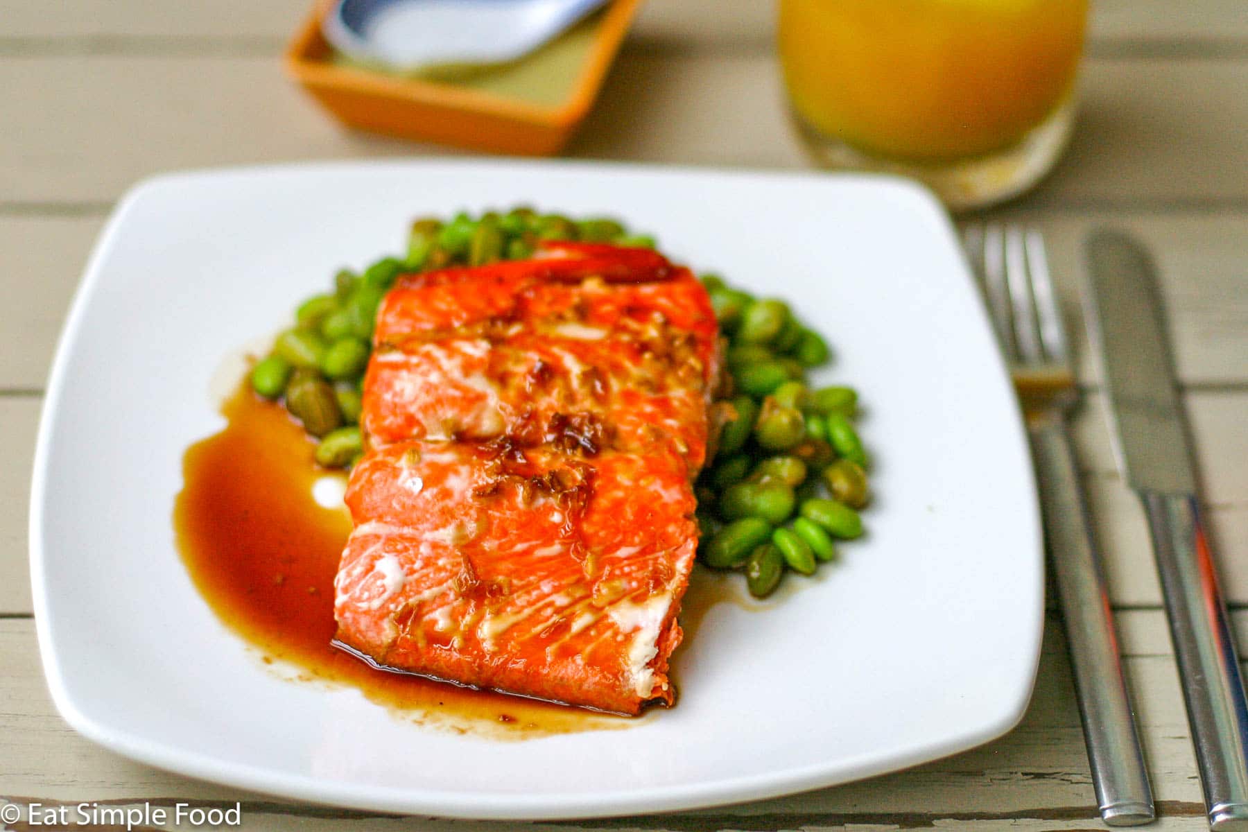 Salmon on square plate with ginger & soy sauce over a bed of shelled edamame - Eat Simple Food
