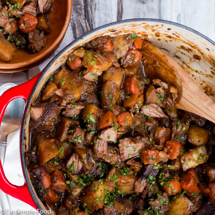 Beef, Carrots, Leeks, Potatoes cooked in a red dutch oven pot with a brown gravy. Top view.