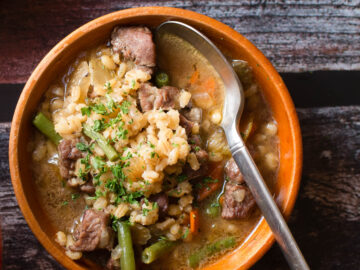 Lamb & Barley Stew in Wooden Bowl with spoon sticking out. Top view.