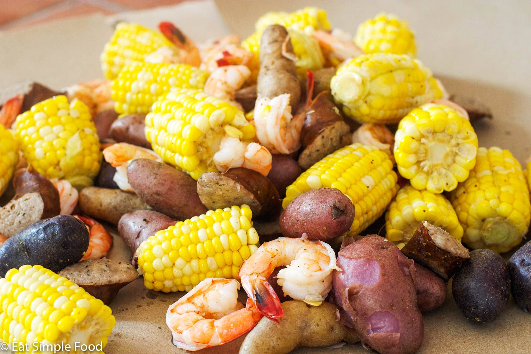 Small Potatoes, Shrimp, Sliced Andouille Sausage, Corn cooked and laid out on craft brown paper.