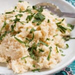Mashed Celery Root (Celeriac) Recipe In White Bowl with celery leave sliced garnish. Spoon on side of plate.