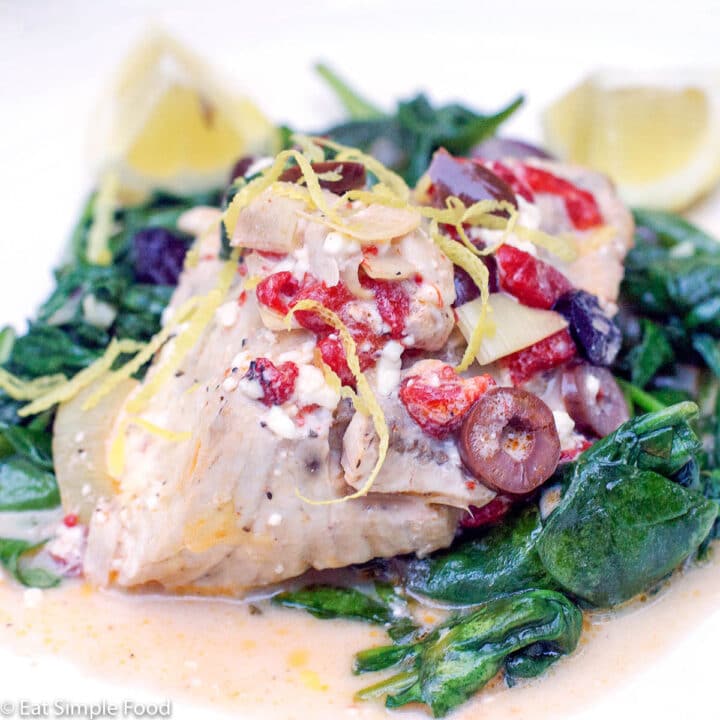 Amberjack Fish On A bed of spinach with kalamata olives, red peppers, lemon zest and lemon wedges.
