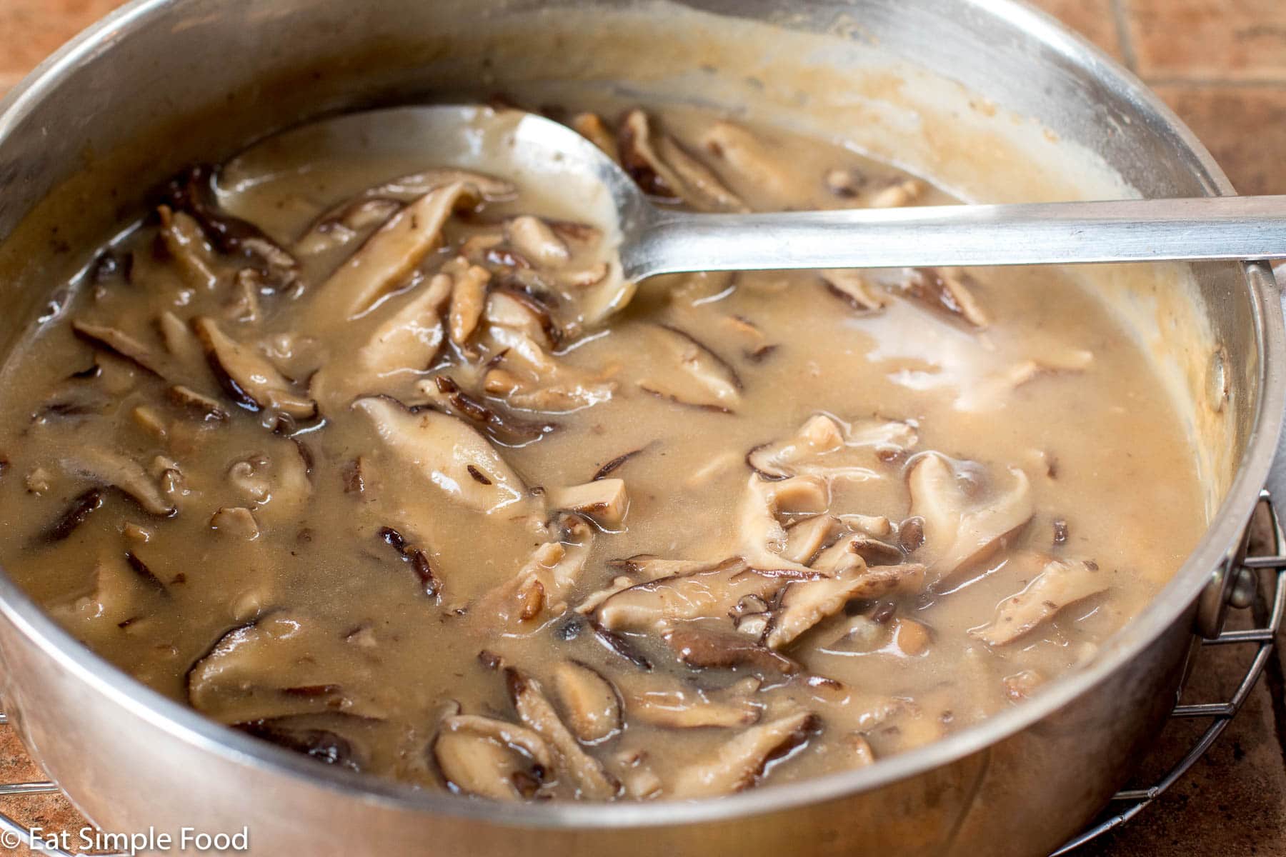 Sliced Mushroom chunky Gravy Recipe in Stainless Steel Pan with A Spoon
