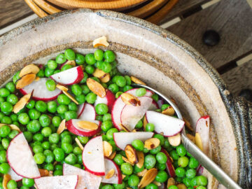Green Sweet Pea, Toasted Sliced Almonds & Thin Sliced Radishes in a brown bowl with a spoon hanging out.