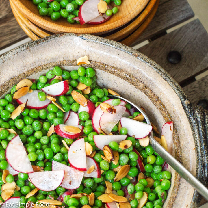 Green Sweet Pea, Toasted Sliced Almonds & Thin Sliced Radishes in a brown bowl with a spoon hanging out.
