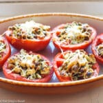 6 tomato halves filled with wild rice, basil pesto, pine nuts, and feta cheese with Parmesan cheese broiled on the top. Close up.