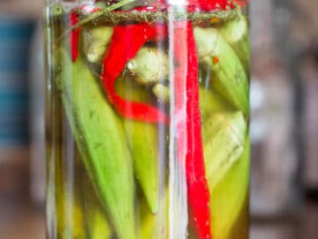 Mason quart jar filled with whole okra and sliced red peppers.