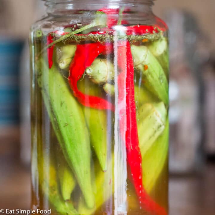 Mason quart jar filled with whole okra and sliced red peppers.