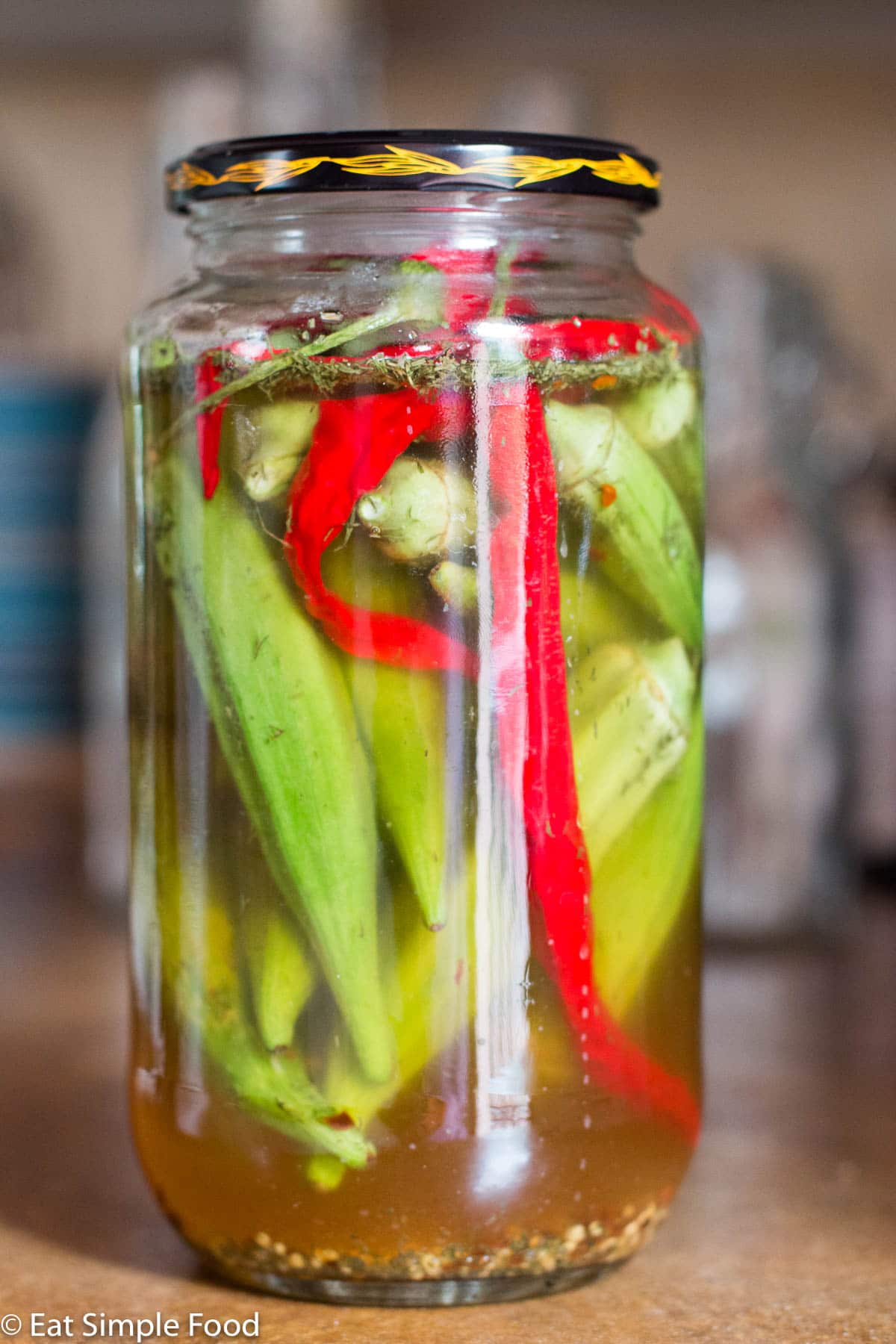 Mason quart jar filled with whole okra and sliced red peppers.