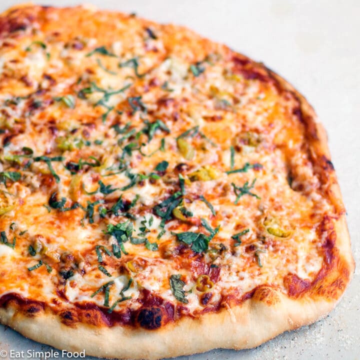 Sliced Pepperoncini, caper, mozzarella cheese, browned pizza topped with fresh sliced basil.