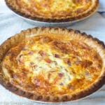1 oven browned Quiche on white towels in a vertical shot. side view
