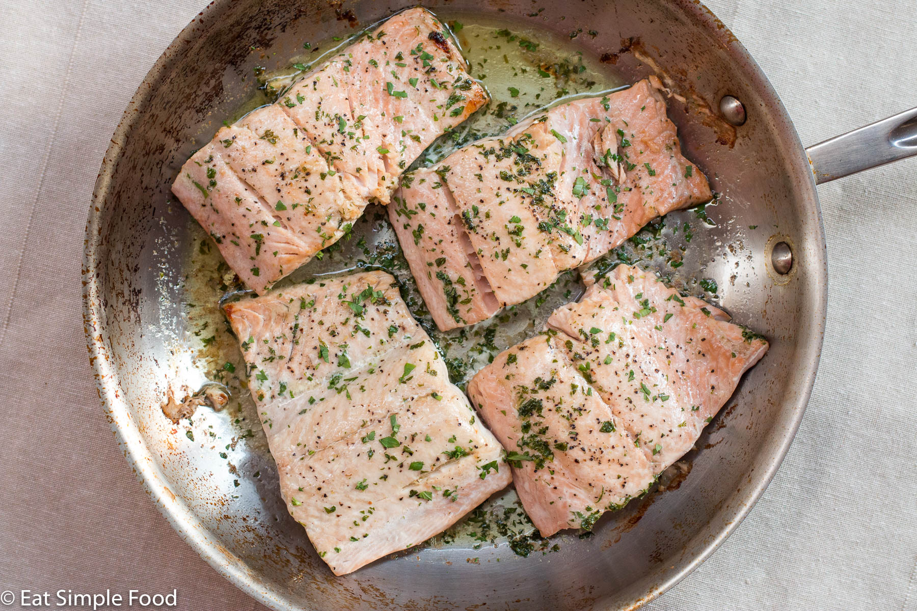 4 Pieces of Roast Salmon In a Stainless Steel Pan. Garnished with chopped parsley