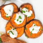 5 Roast Sweet Potato Slices on a white plate with a dollop of sour cream and chive garnish.